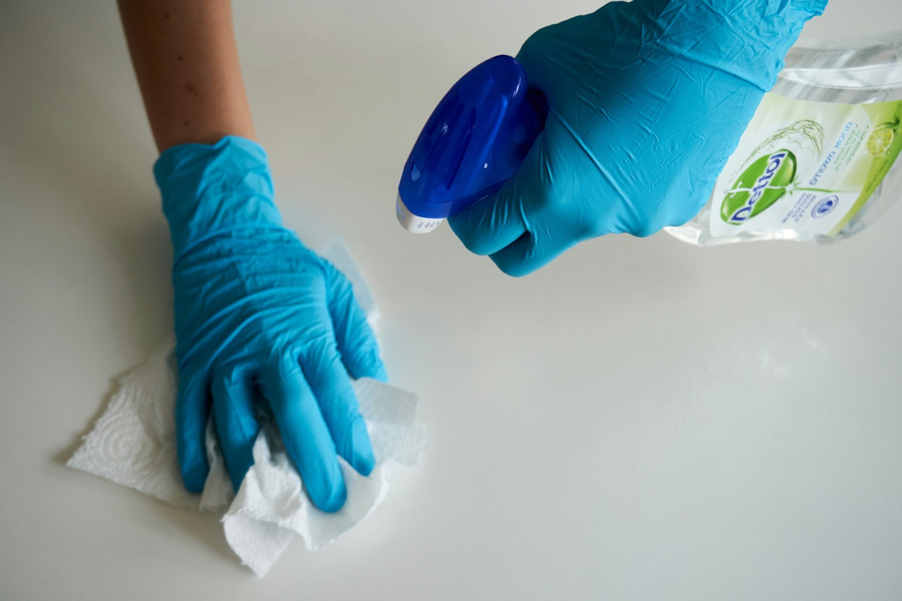 Gloved hands wiping a surface with a cleaning cloth